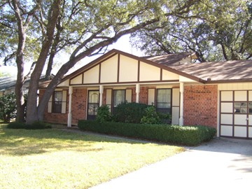big front porch and oak trees shading home
