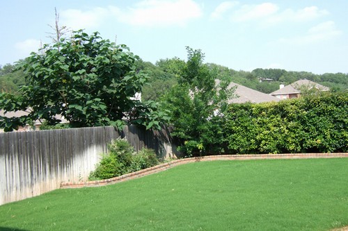 landscaped, fenced yard with brick planters and a view of the hills